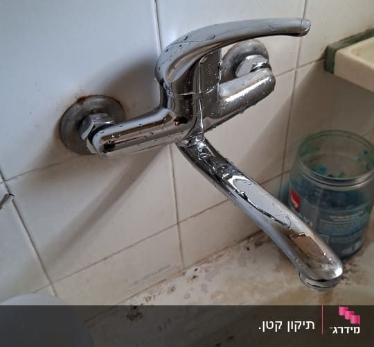 ברז מים על קיר עם כיור ישן